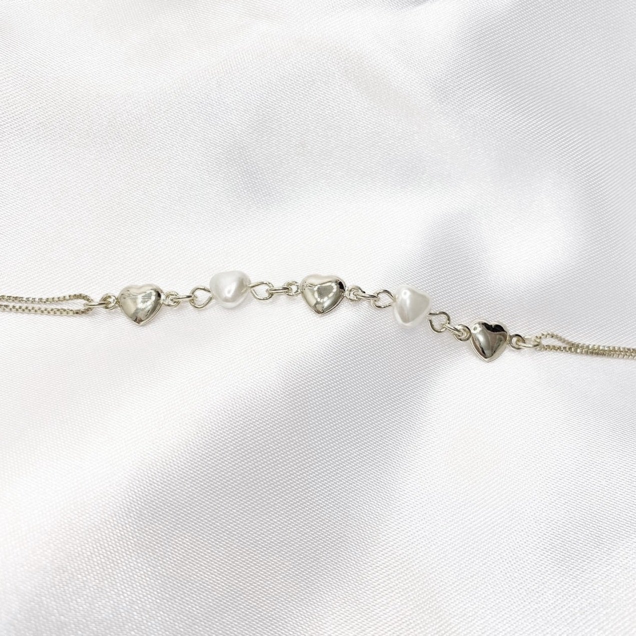 PULSEIRA COM CORAÇÕES E PÉROLAS EM CORAÇÃO COM 18 CM EM RÓDIO BRANCO